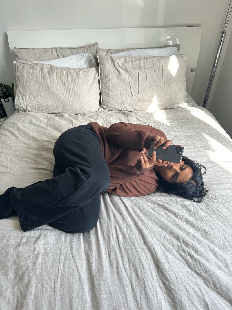 Vrouw ligt op bed en kijkt op haar telefoon